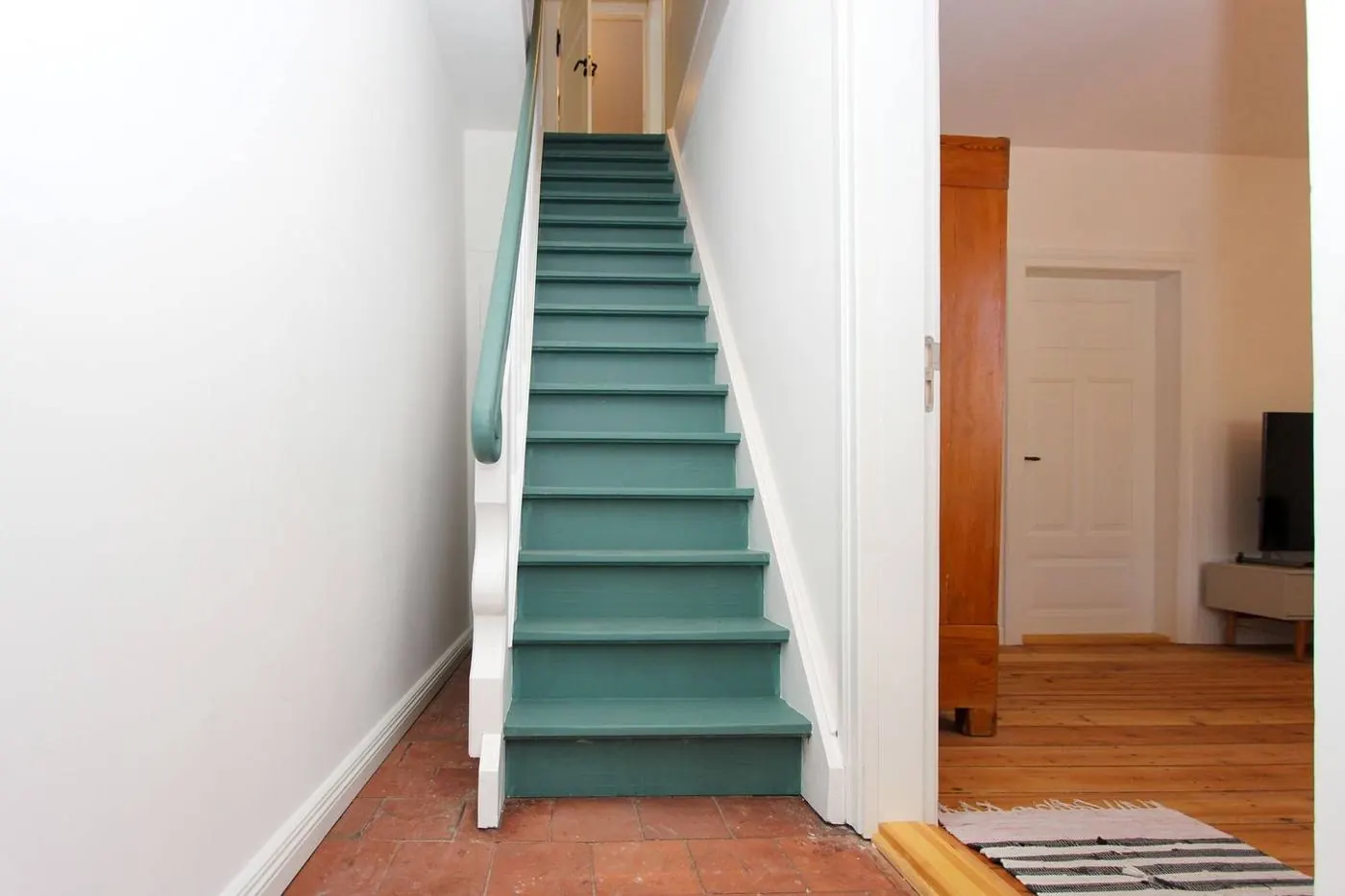 Flur mit Klinkerboden und grün gestrichener Treppe