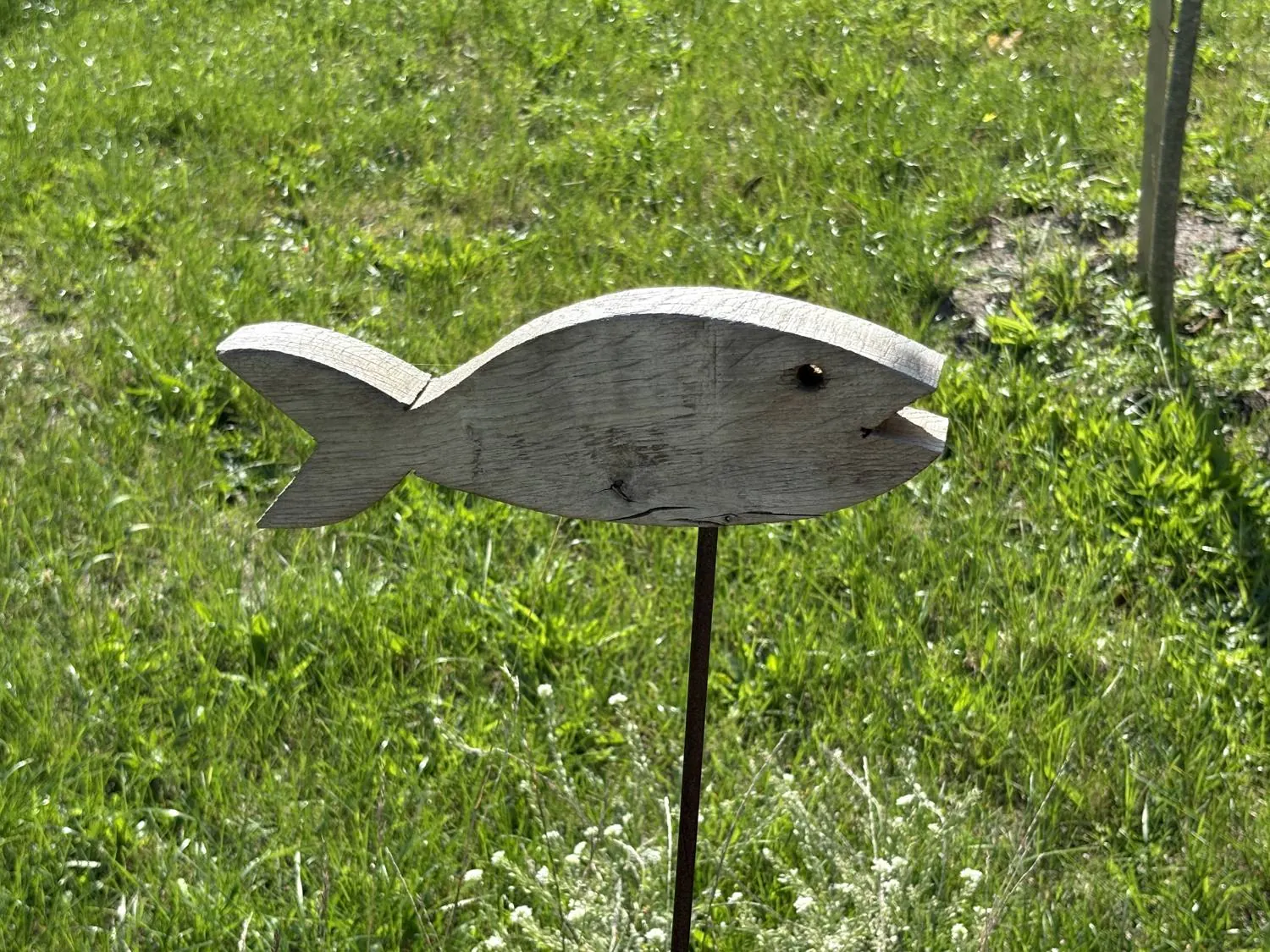Ein Holzfisch auf einem Metallstab in der Wiese