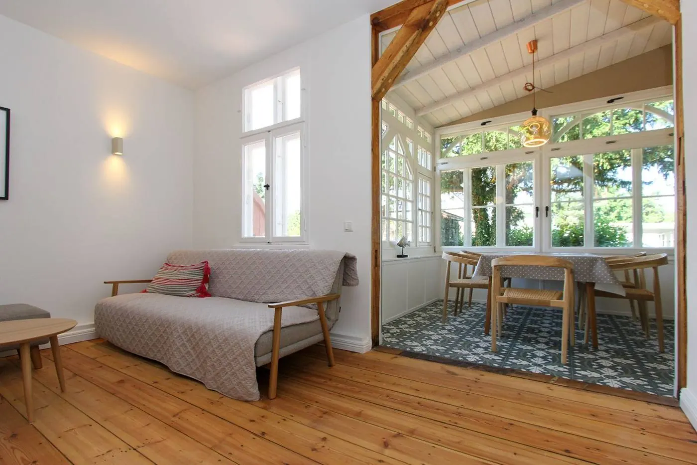 Wohnzimmer mit Sofa und Blick in die Veranda mit Holzbalken